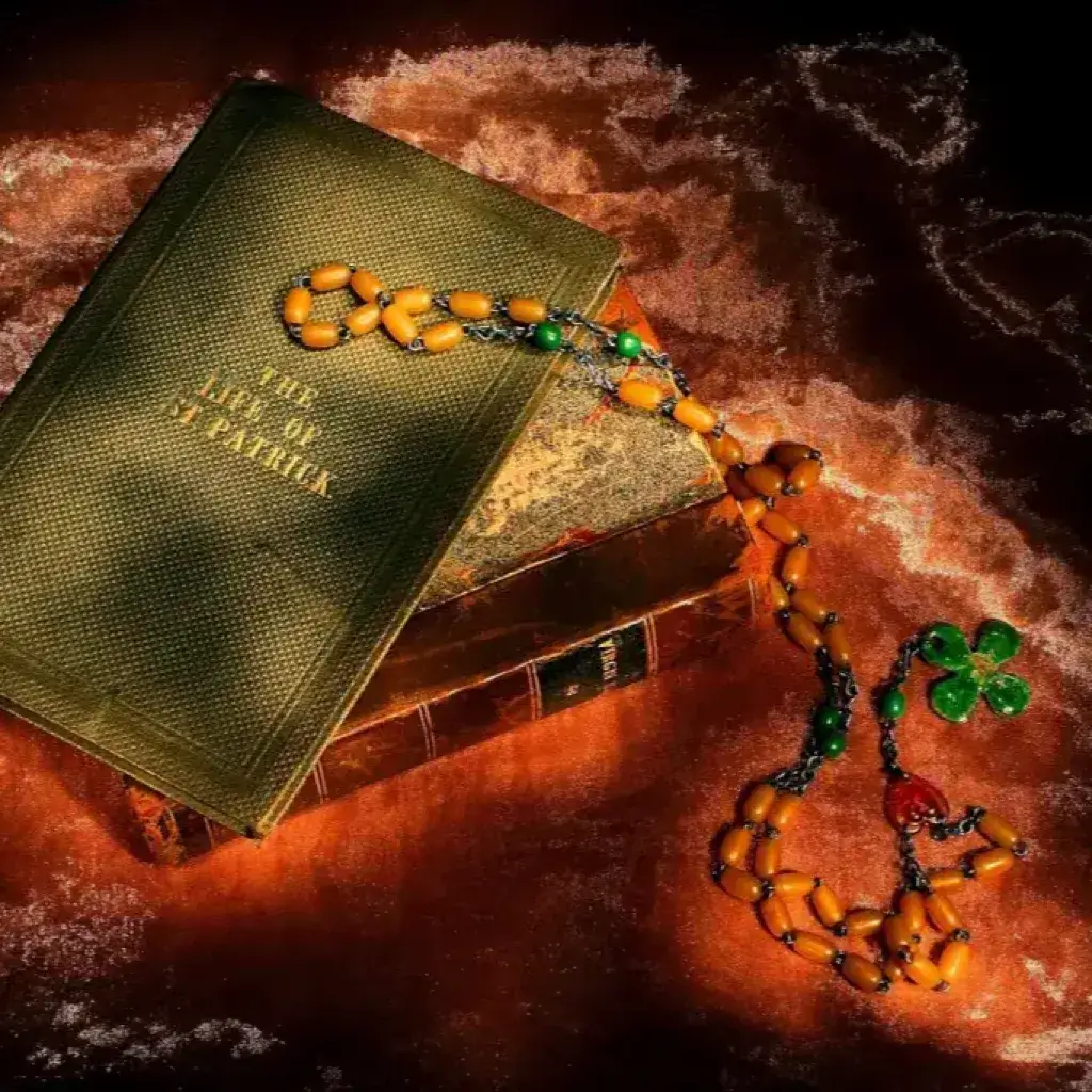 Altes Buch 'The Life of St Patrick' mit Rosenkranz und Kleeblatt in warmem Licht